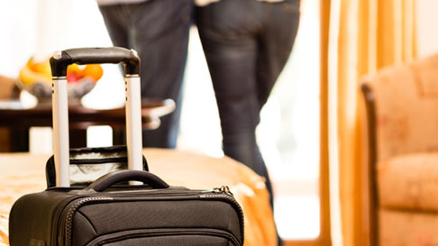 suitcase in hotel room with couple in background