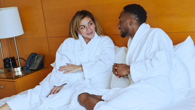 couple laughing on bed in hotel room